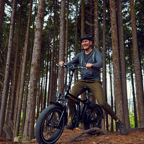 Person in a helmet riding an electric fat tire bike on a trail with trees in the background