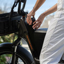 Woman riding a RadRunner 3 Plus electricc utility bike with accessories installed, including a console to store small items.