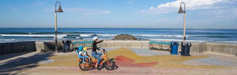 A mother rides with her children on a RadWagon along the coast in San Diego