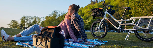 Couple sits with a picnic next to their Rad Power Bike.