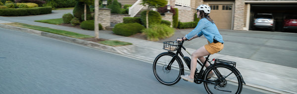 A woman rides a RadMission electric metro bike up a hill in her neighborhood.