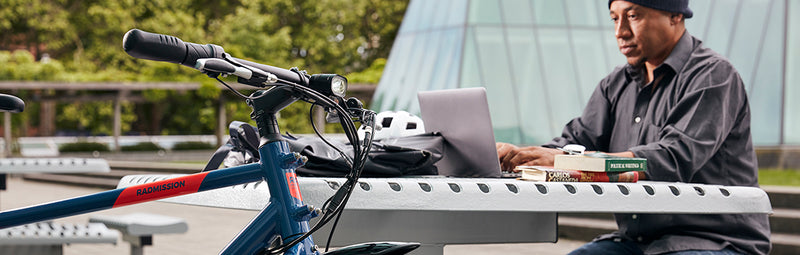 A man works on his laptop alongside his RadMission electric metro bike.