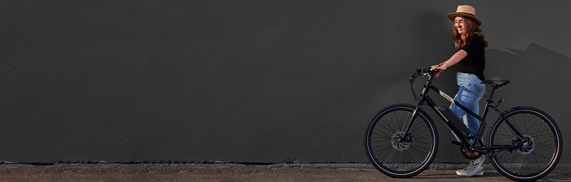 A woman rides a RadMission electric metro bike alongside a black background.