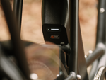 A Safe Shield battery with the charge indicator illuminated mounted on a matte black ebike