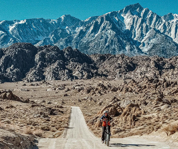 Person riding an electric bike on a road with mountains in the background