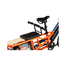 A side profile view of an orange RadWagon, with a black Deckpad cushion mounted on the rear rack