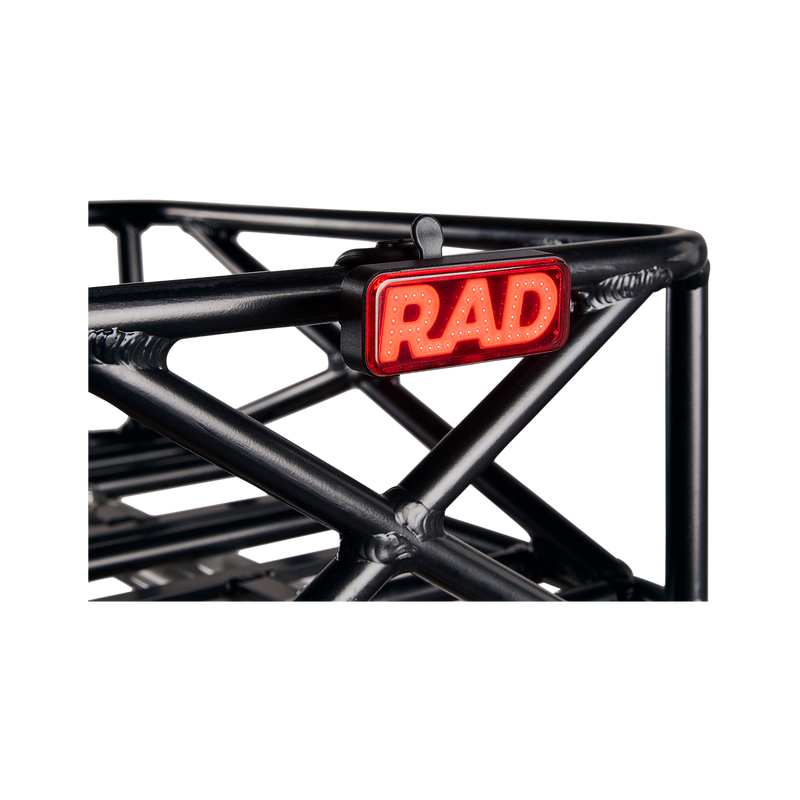 Close up picture of Rad Power Bikes Rad logo taillight mounted on a bicycle basket.