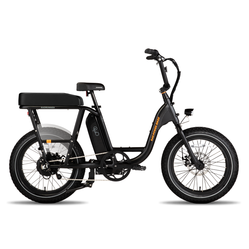 Side view of black RadRunner ebike with black Passenger Package seat on rear rack, clear plastic skirt covers near the rear wheel and retractable passenger foot pegs.