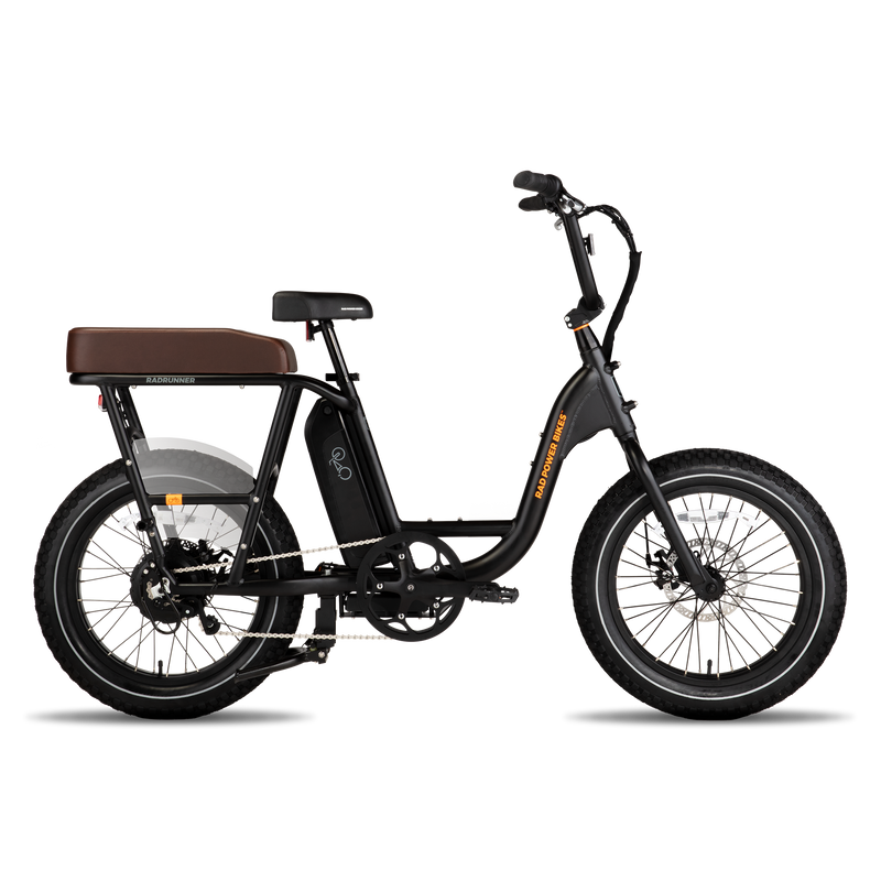 Side view of black RadRunner ebike with espresso Passenger Package seat on rear rack, clear plastic skirt covers near the rear wheel and retractable passenger foot pegs.