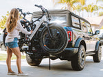 A person loads two ebikes onto a Sport Rider rack on the back of a vehicle