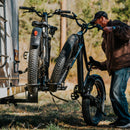 Lifestyle photo of a man removing one of two ebikes from a RV Rider Rack mounted on an RV