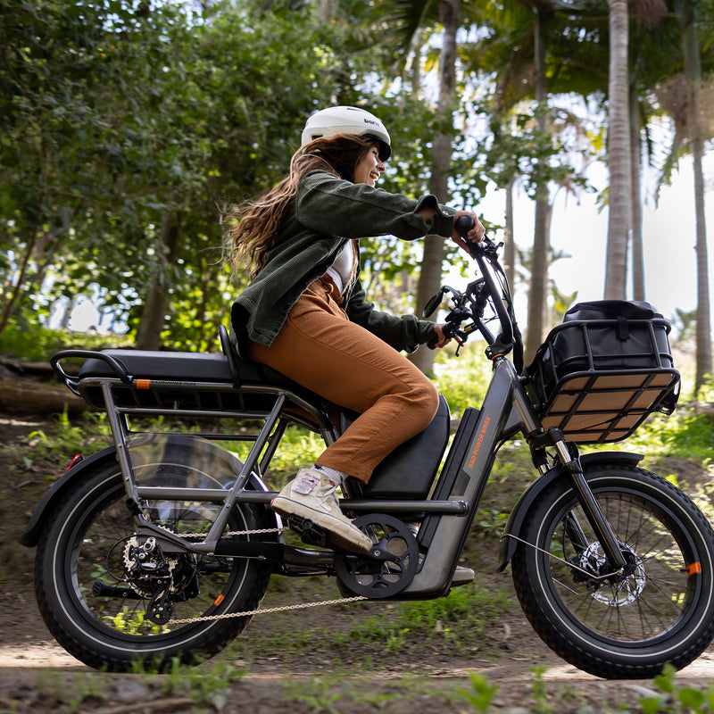 Woman riding a RadRunner 3 Plus electricc utility bike with accessories installed, including a console to store small items.