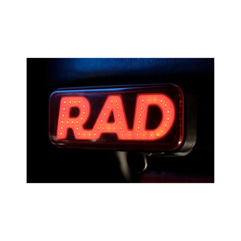 Close up photo of Rad Power Bikes Rad Logo taillight mounted on a bicycle at night with light turned on.